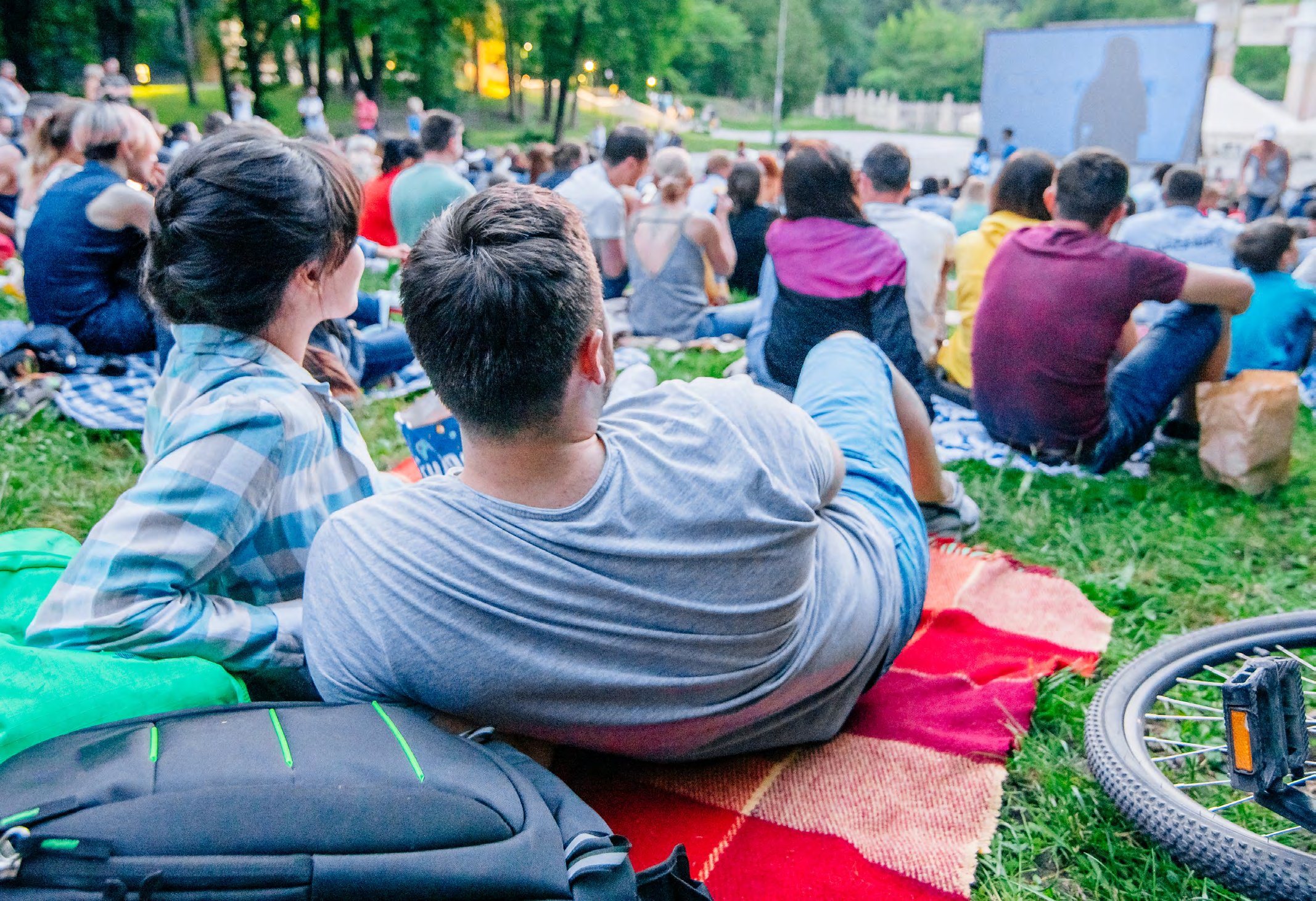 People seated on the lawn watching an outdoor movie in a Grimsby park
